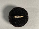 a gold ring with a diamond in it sitting on a black ring holder