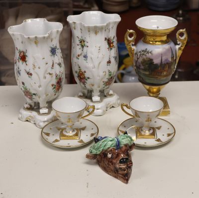 five cups and saucers on a table with a dog figurine