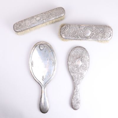 trois cuillères en argent et un pinceau posés sur une surface blanche