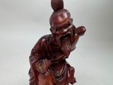 a statue of a man sitting on a stool with a cane
