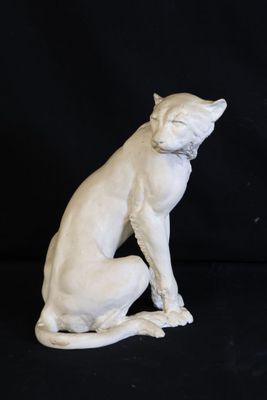 statue of a cat sitting on its hind legs on a black background