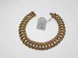 gros plan d'un bracelet en chaîne en or sur une surface blanche