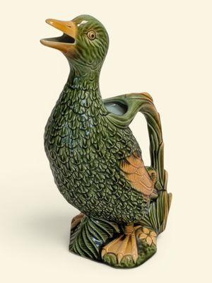 a green bird that is sitting on top of a vase