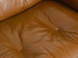 a brown leather chair that has a small hole in it