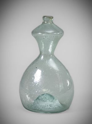 a green glass vase with a small wave inside of it