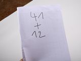 a person holding a piece of paper with a number written on it