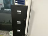 a black filing cabinet in the corner of a room