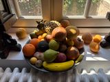 a bowl of fruit on a window sill next to a radiator