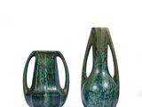 deux vases verts posés l'un à côté de l'autre sur une surface blanche