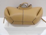 beige leather handbag sitting on top of a box on a white surface