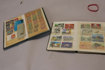 deux livres ouverts, sur lesquels figurent des timbres, posés sur une table