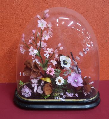 un dôme en verre contenant des fleurs, posé sur une table