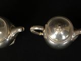 two silver teapots on a black background with a black background
