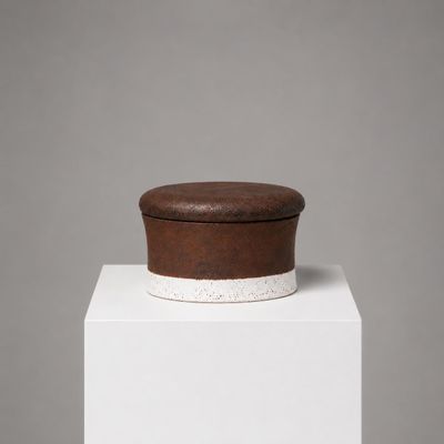 une petite boîte marron posée sur un socle blanc