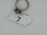 a close up of a key ring on a tag on a white surface