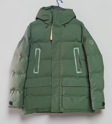 La veste verte est suspendue à un cintre accroché à un mur blanc.