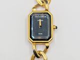 a gold watch with a black face on a chain bracelet