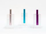 trois vases en verre de couleurs différentes posés côte à côte sur une surface blanche
