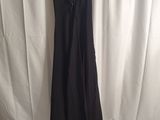 a black dress hanging on a hanger in front of a white curtain