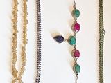 a lot of different necklaces and bracelets hanging on a wall