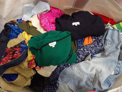 un tas de vêtements dans un bac en plastique posé par terre