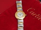 une photo d'une montre-bracelet dorée et argentée posée sur un coffret rouge