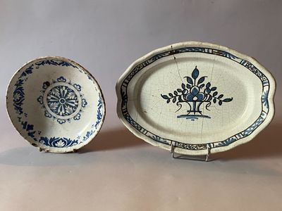 two blue and white plates with designs on them sitting next to each other