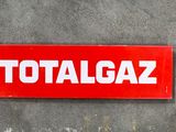 une enseigne rouge portant l'inscription « totalgaz » sur le mur d'un immeuble