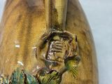 a hand holding a vase with a bird on it