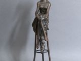 statue représentant une femme assise sur un tabouret, coiffée d'un chapeau