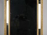 a gold framed mirror sitting on top of a white table