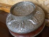 a silver plate sitting on a wooden table next to a wall