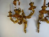 two gold colored sconces on the wall next to each other