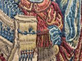 un gros plan sur une tapisserie représentant un homme tenant un livre