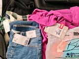 a bag of clothes and a pair of jeans sitting on the floor