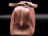 a close up of a brown leather bag on a black surface