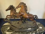 statue représentant deux chevaux, posée sur un socle en marbre, elle-même posée sur une table