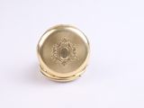 a close up of a gold pocket watch on a white surface