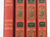 quatre livres rouges sont alignés sur une surface blanche