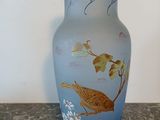 a blue vase with a bird on it sitting on a table