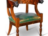 une image représentant une chaise en bois avec une assise verte et une tête de lion sur le dossier