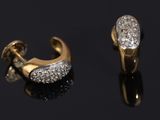 two pairs of gold and diamond earrings on a black surface