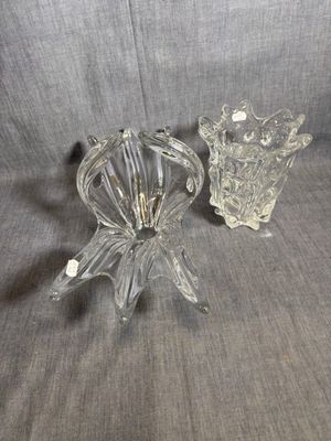 une paire de bougeoirs en verre transparent posés sur un tissu gris
