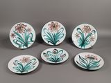quatre assiettes sur lesquelles sont peints des fleurs et des feuilles sur un fond gris