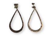 une paire de boucles d'oreilles en argent martelé en forme de larme sur fond blanc
