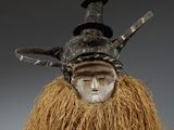 un gros plan sur un masque orné d'une longue barbe et d'un chapeau posé dessus