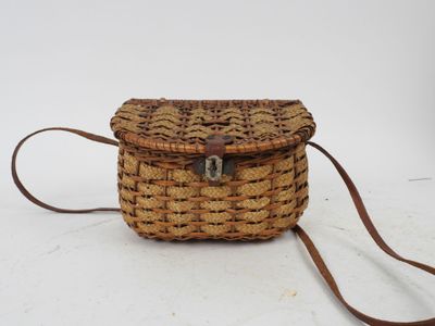 an old woven purse with a leather strap on a white background