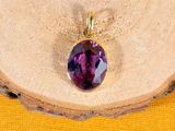 a close up of a purple stone pendant on a piece of wood