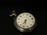 a silver pocket watch with roman numerals on it