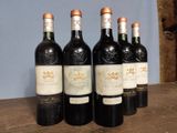 several bottles of wine are lined up on a wooden table
